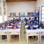 les petits élèves et deux des architectes : Dorian Vauzelle et Frank Stabel à l'école maternelle bioclimatique d’Aknaibich, au Maroc © Kristel Pelliet