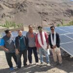 Plusieurs hommes posent pour la photo devant les panneaux solaires alimentant la pompe à eau solaire dans un internat du Ladakh