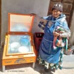 Bénéficiaire femme posant devant son cuiseur solaire